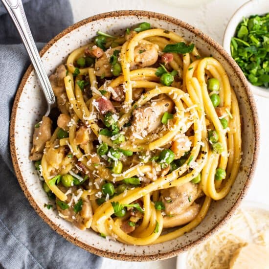 A bowl of pasta with chicken and parsley.