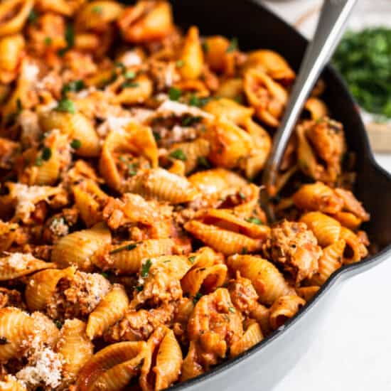 ground turkey pasta in a cast iron skillet with a spoon