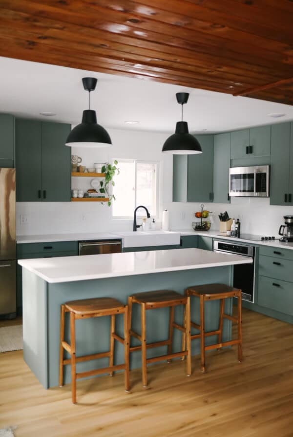 A kitchen with green cabinets and wood floors.