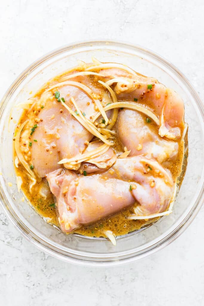 Chicken thighs marinating in a bowl.