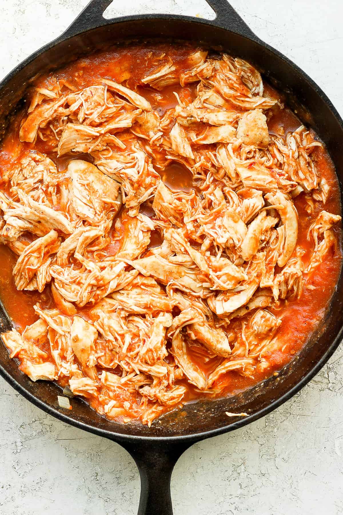 Shredded chicken and tinga sauce in a cast iron skllet.