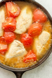 Chicken and tomatoes in a skillet.