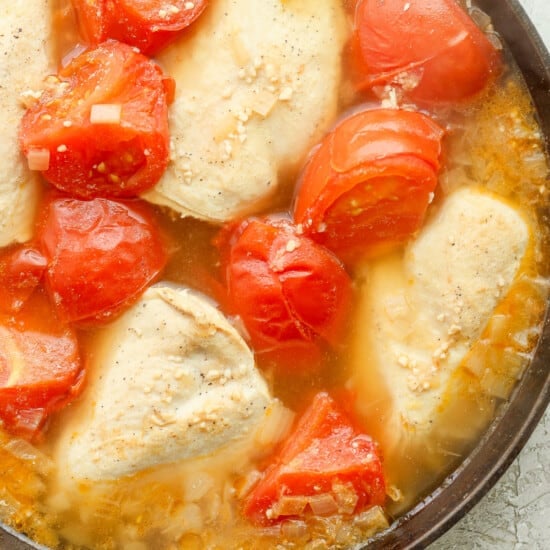 Chicken and tomatoes in a skillet.