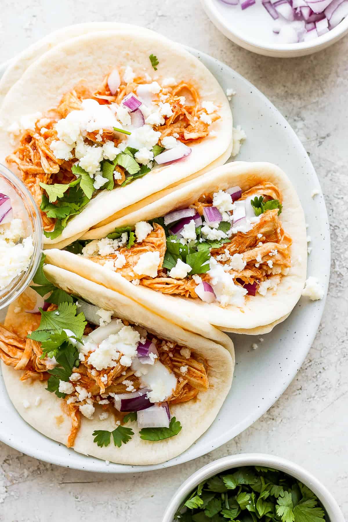Chicken tinga tacos with fresh cilantro, red onion, and cotija cheese on top. 