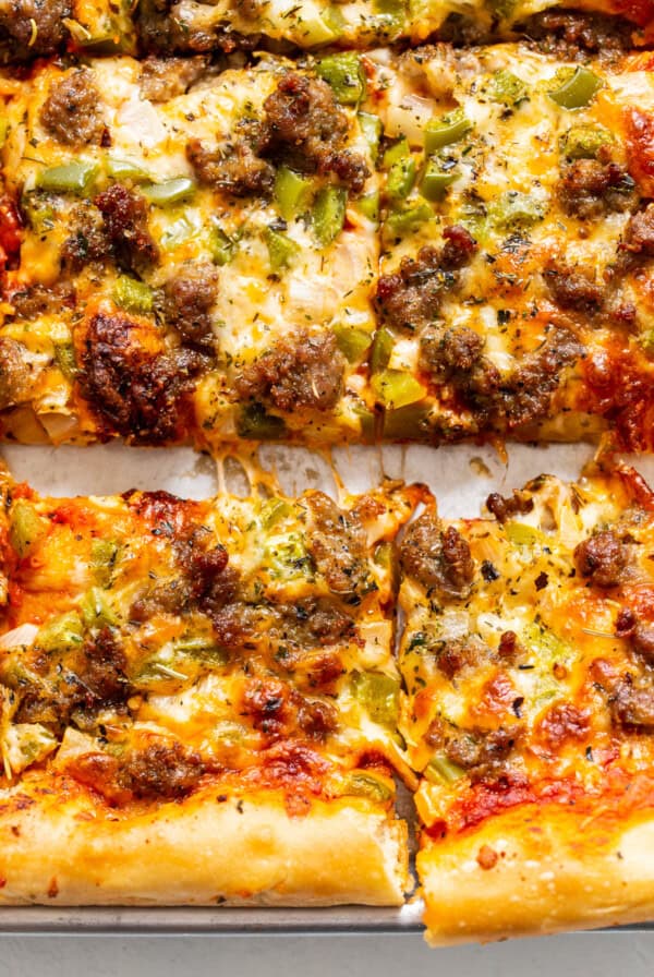 A pizza with sausage and peppers on a tray.