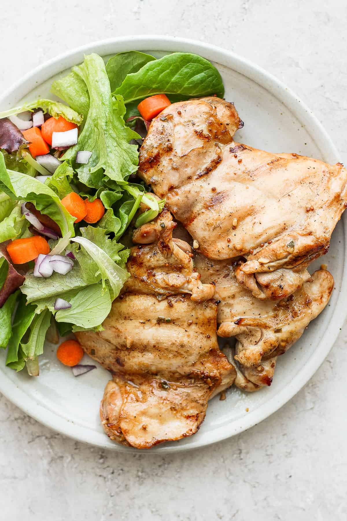grilled chicken thighs on plate with greens.