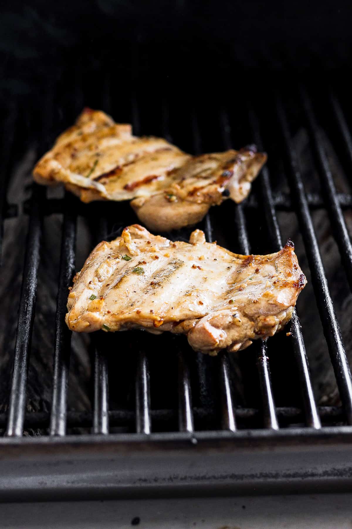 boneless skinless chicken thighs on grill grates.