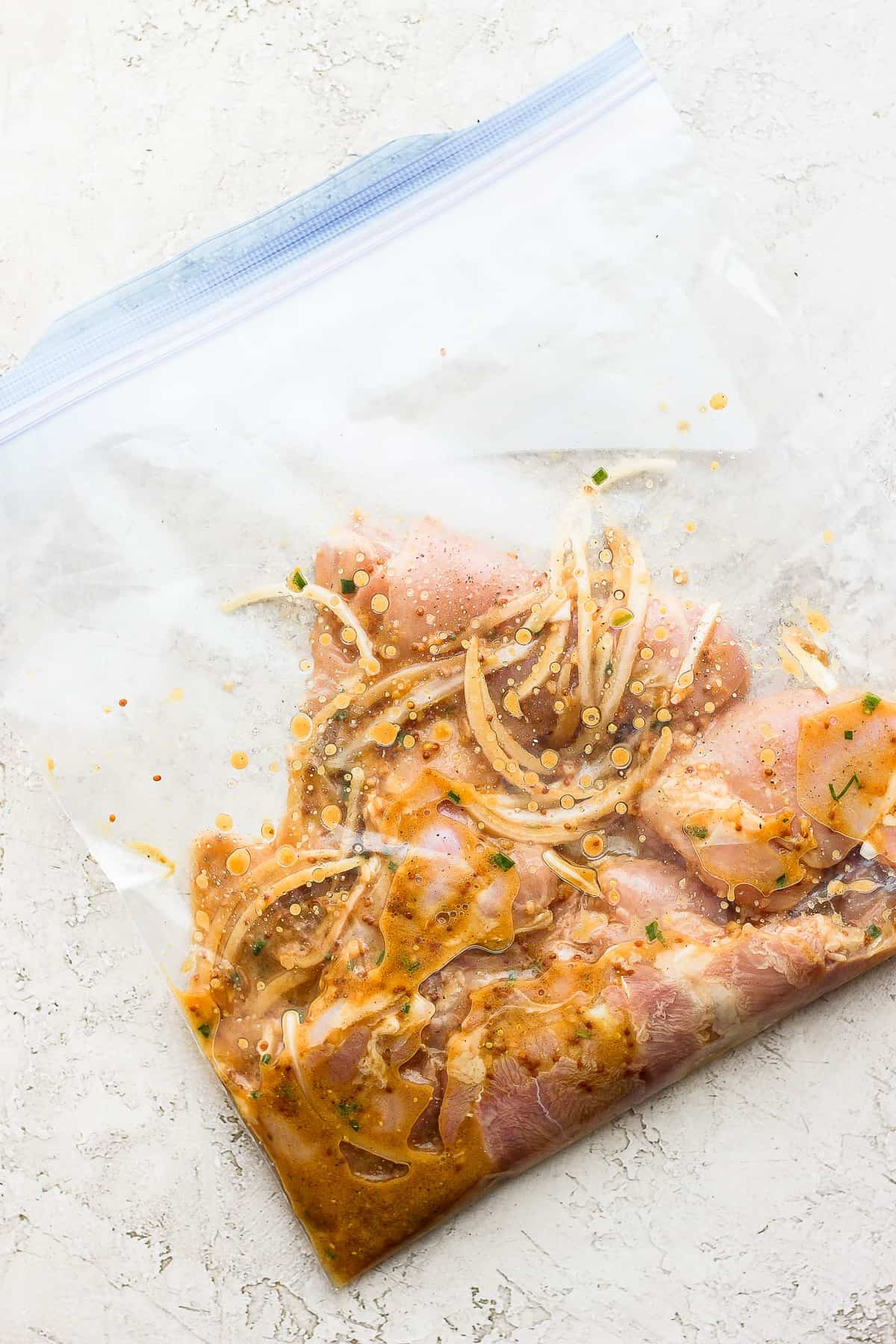 Chicken thighs and a marinade in a gallon size bag.