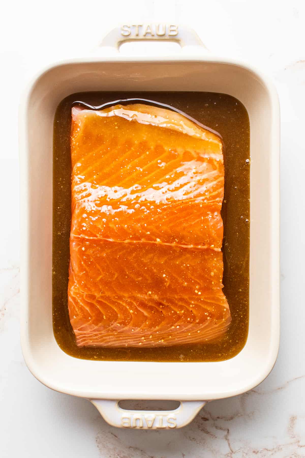 A salmon filet marinating in a dish. 