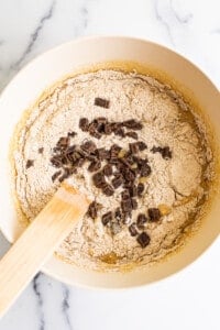 Chocolate chip cookie dough in a bowl with a wooden spoon.