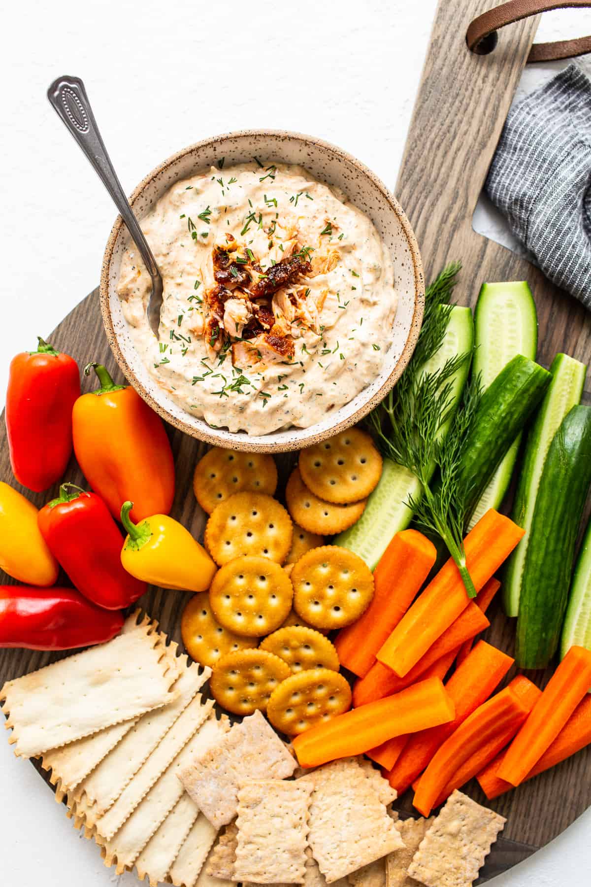 Smoked salmon dip in a bowl with crackers and veggies.