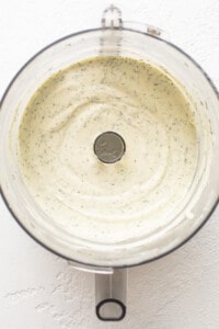 A food processor filled with a green sauce.