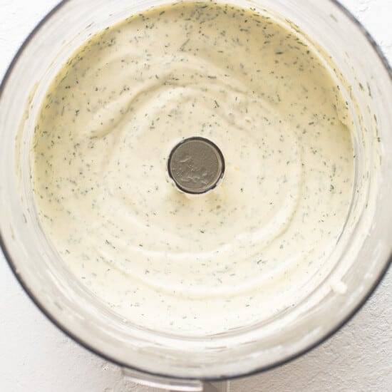A food processor filled with a green sauce.