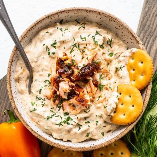 Salmon dip in a bowl with crackers and vegetables.
