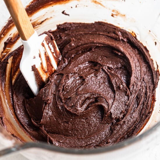 Chocolate cake batter in a bowl with a wooden spoon.