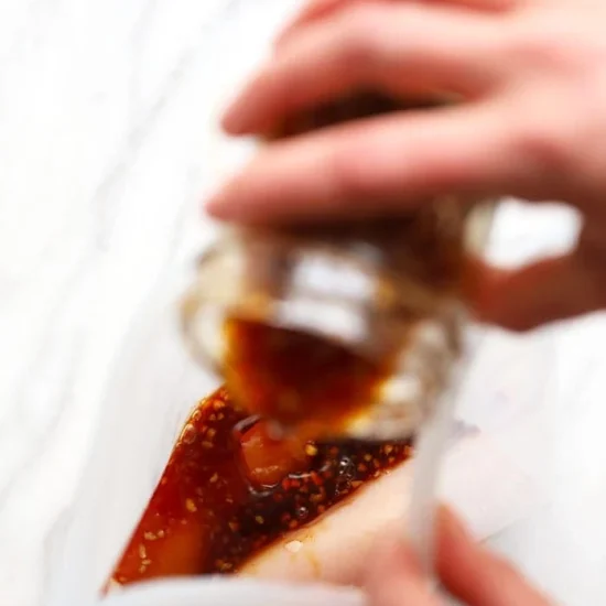 A person pouring homemade teriyaki sauce into a plastic bag.