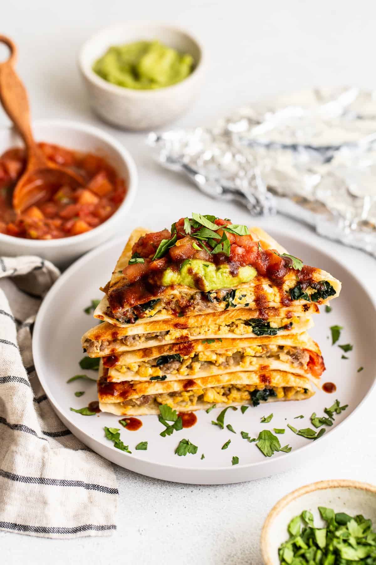 Slices of breakfast quesadillas on a plate topped with salsa and guacamole.