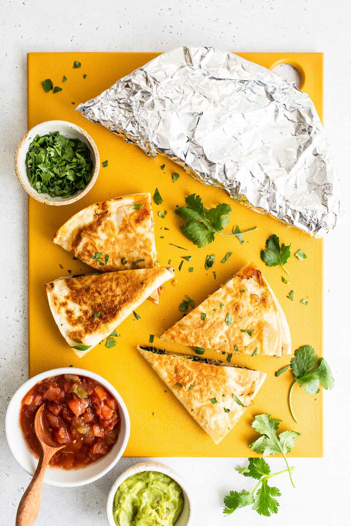 Slices of breakfast quesadillas on a cutting board.