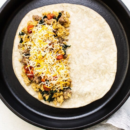 A green skillet filled with a breakfast burrito.