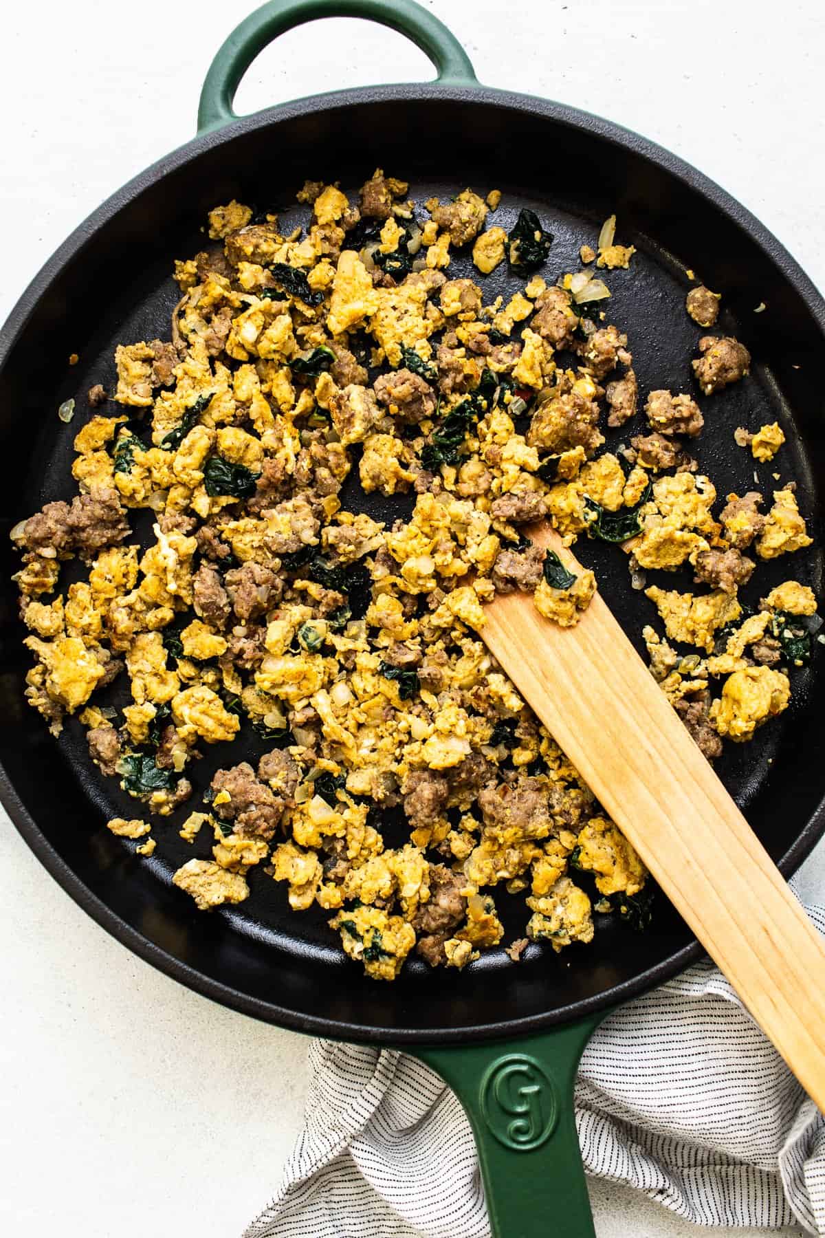 Scrambled eggs, breakfast sausage and kale sauteed in a cast iron skillet.