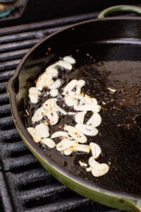 A pan with garlic on it on a grill.