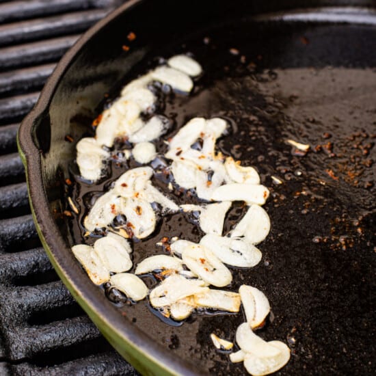 A pan with garlic on it on a grill.
