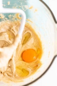 A bowl of batter with an egg in it.