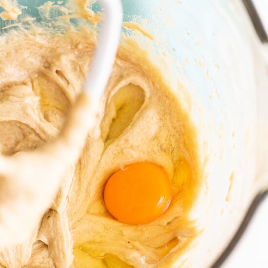 A bowl of batter with an egg in it.