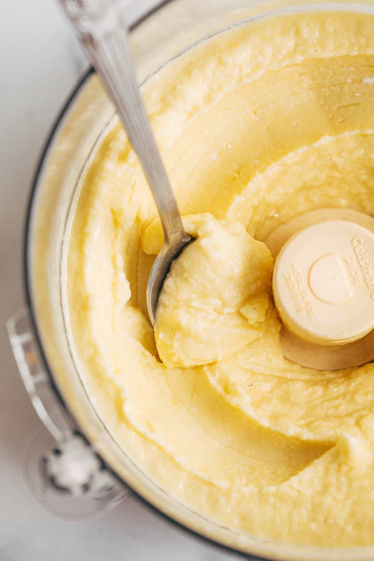 Dole whip in a food processor with a spoon.