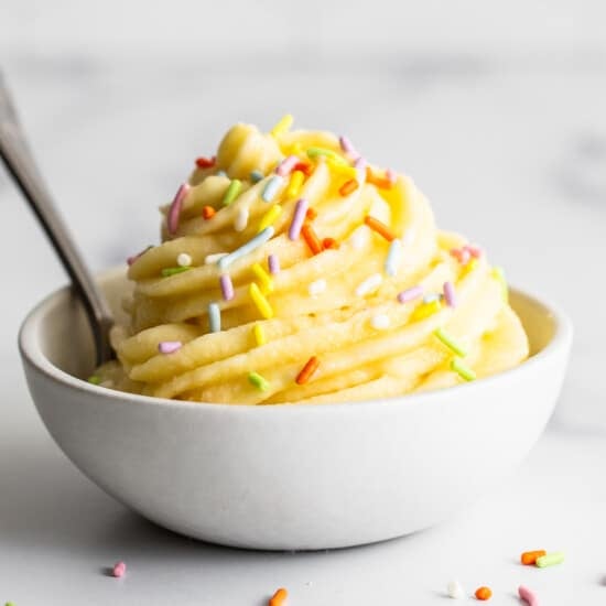 A bowl of ice cream with sprinkles and a spoon.