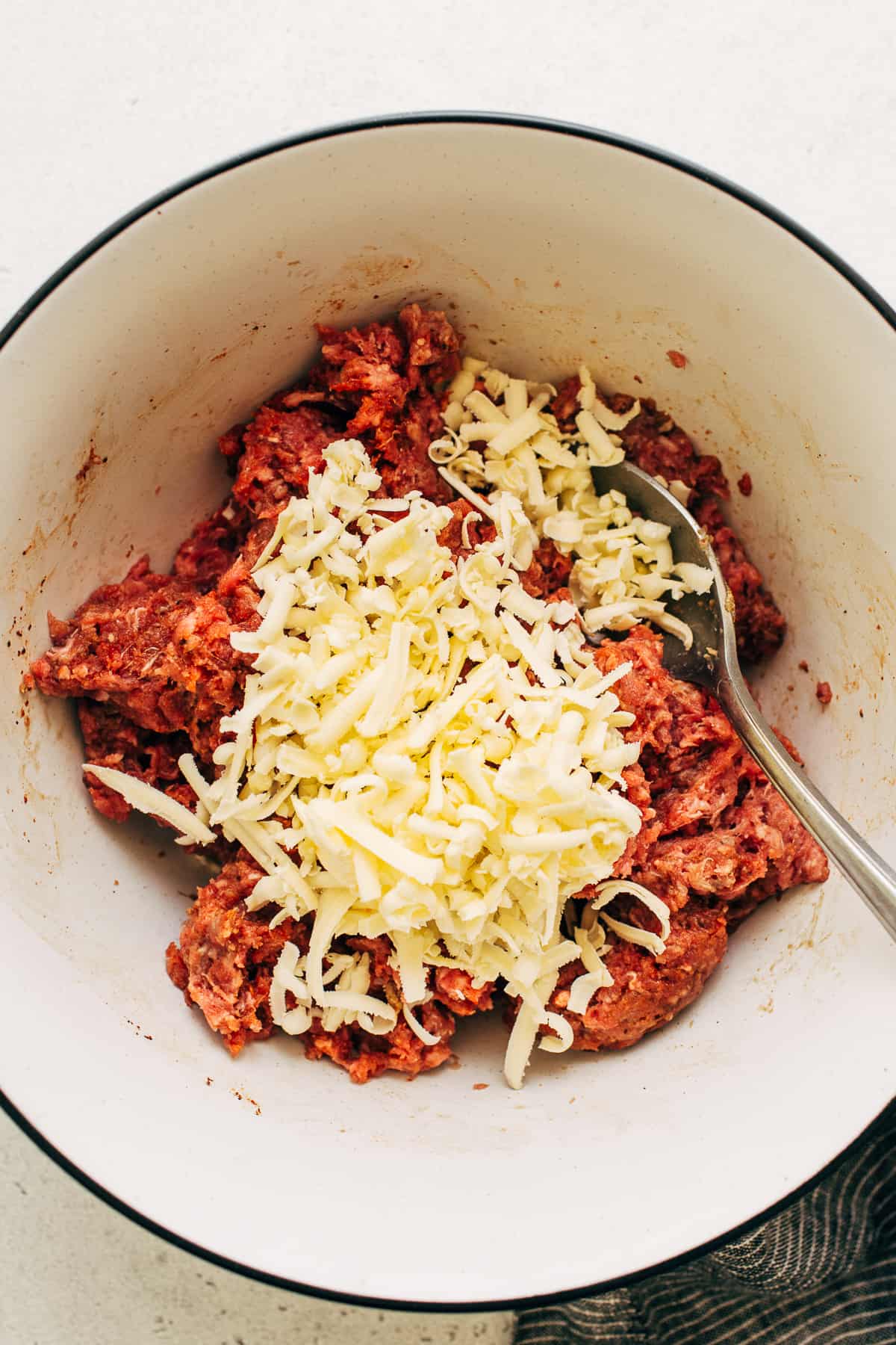 Homemade burger mixture topped with grated butter in a bowl.