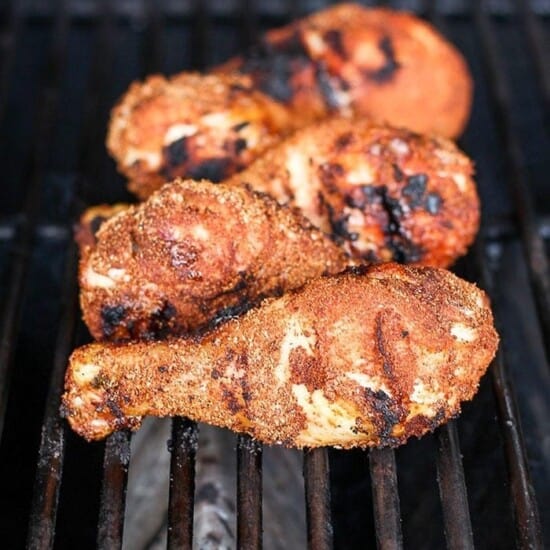 A close up of grilled chicken legs on a grill.