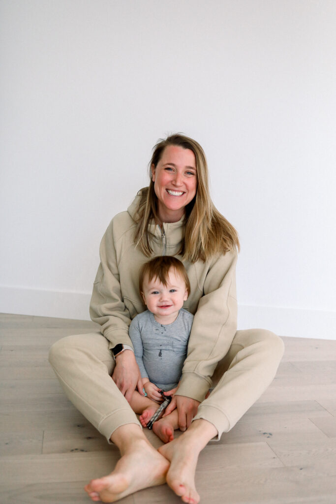 Woman and a baby sitting on the ground.