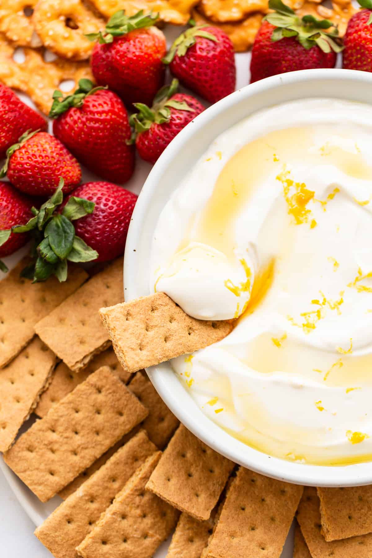 Fruit dip surrounded by strawberries and graham crackers.