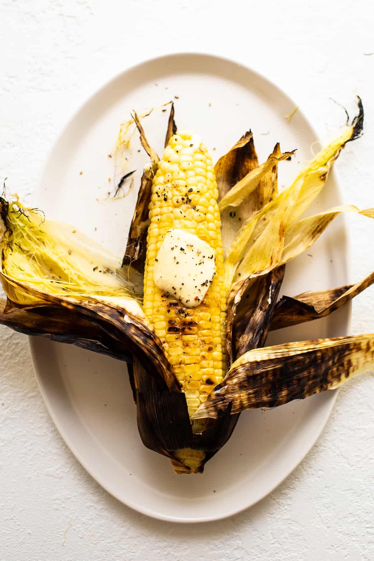 grilled corn on a plate with butter.