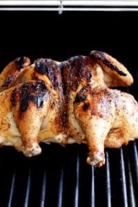 grilling whole chicken on grill grates.