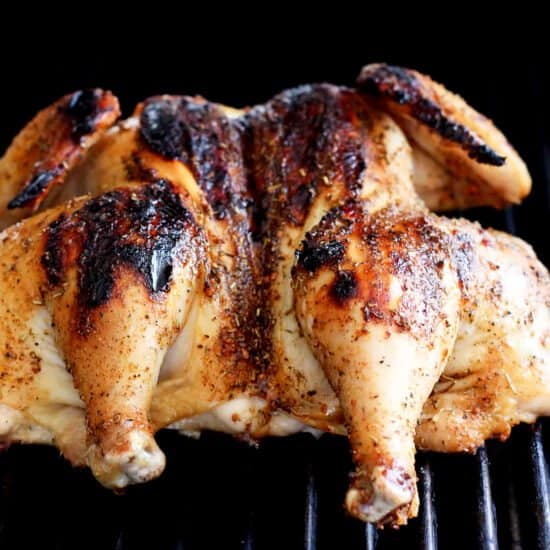 grilling whole chicken on grill grates.