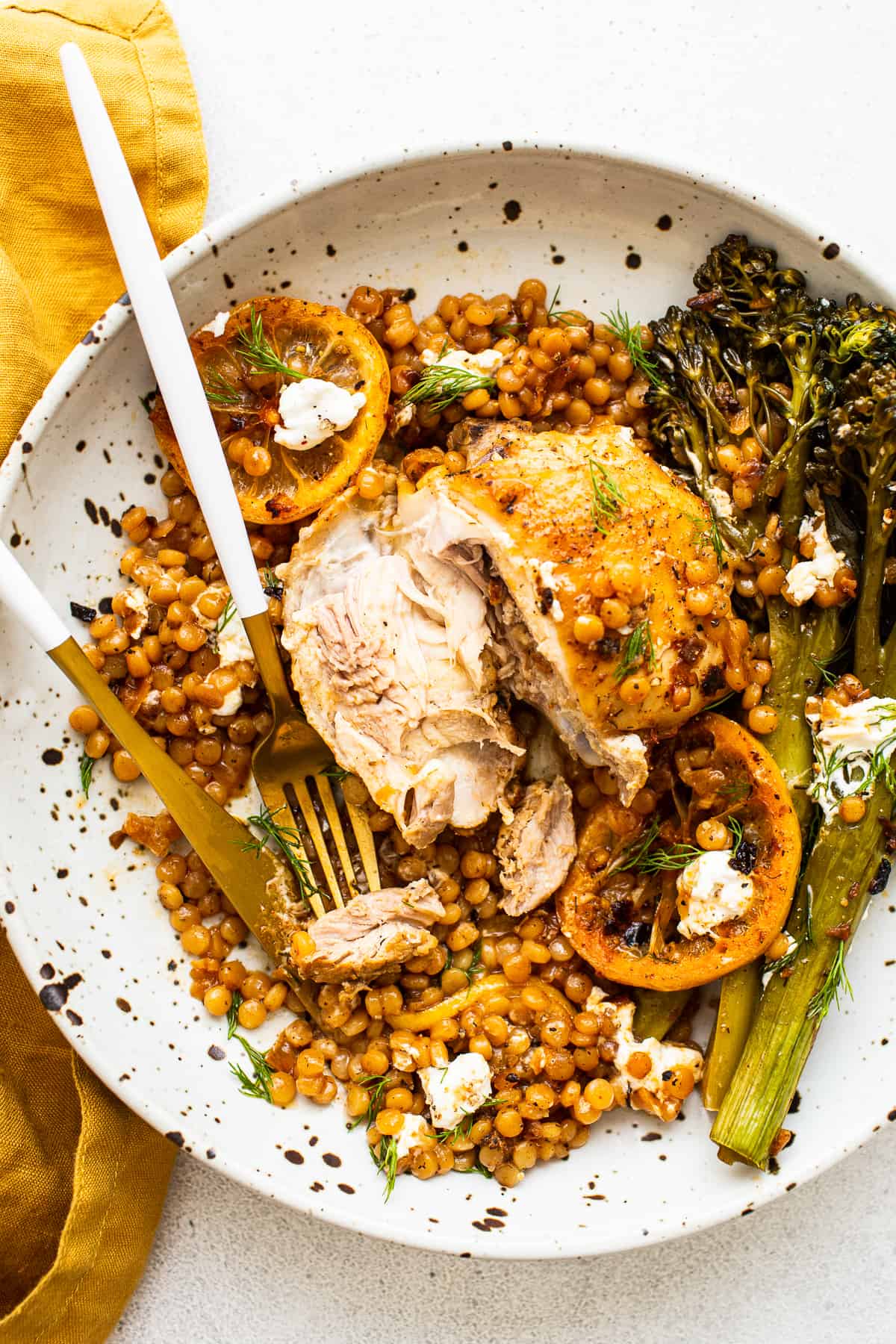 Lemon chicken skillet on a plate with broccolini and couscous.