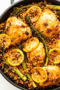 A skillet filled with chicken, broccoli and lemons.