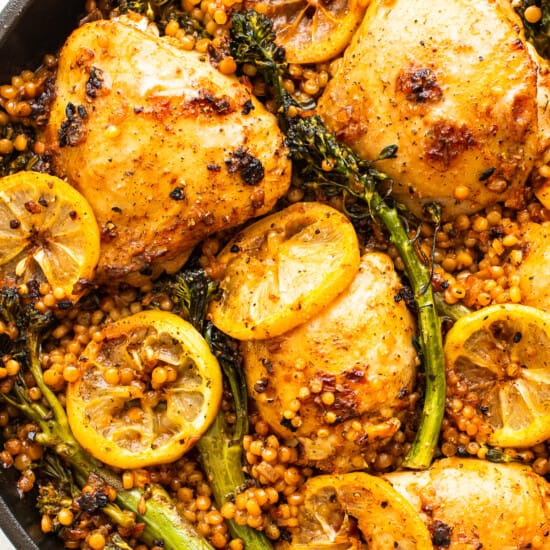A skillet filled with chicken, broccoli and lemons.