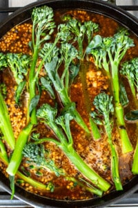 A pan with broccoli in it cooking on the stove.