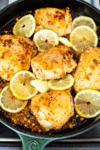 Chicken in a skillet with lemon slices.