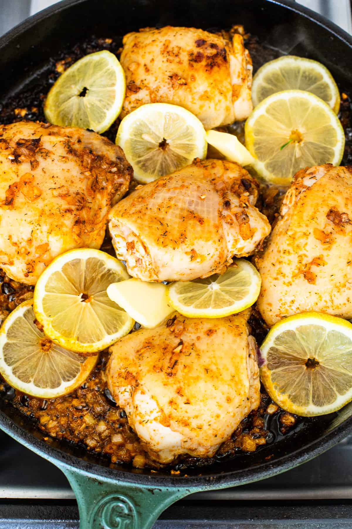 Chicken thighs in a skillet with lemon slices.