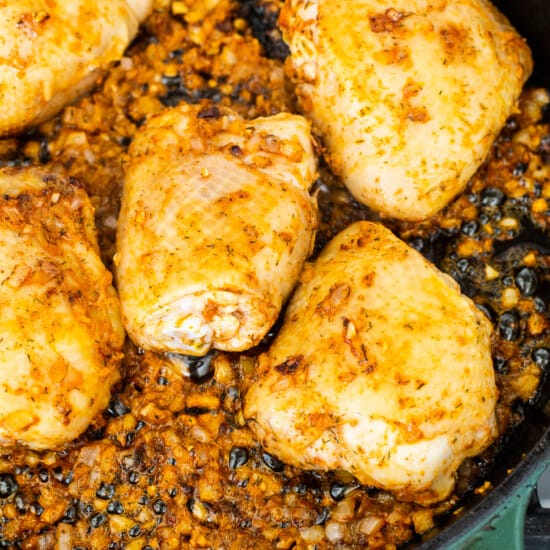 Chicken breasts in a skillet on a stove top.
