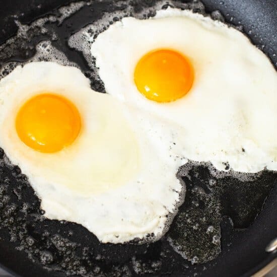 Two eggs are being fried in a frying pan.