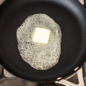 Butter in a frying pan on a stove.