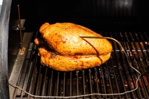 A turkey breast smoking on a smoker.