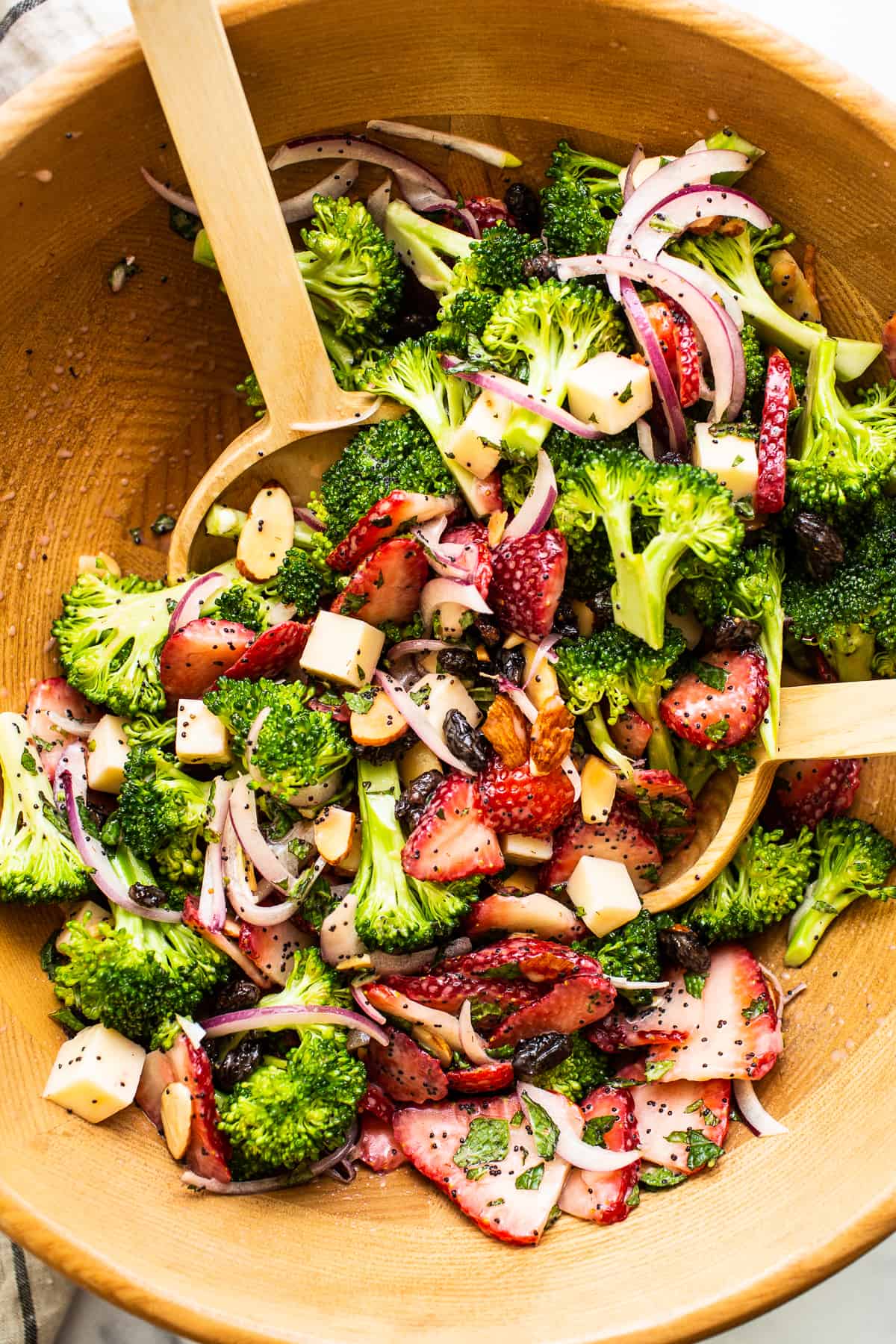 This strawberry broccoli salad is tossed in a homemade poppy seed dressing for the ultimate summer salad. Enjoy as a side or a main dish! Strawberry broccoli salad in a wooden bowl.
