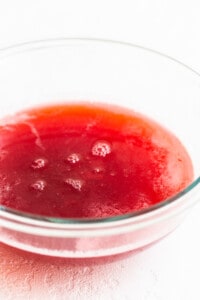 A bowl of red liquid on a white surface.