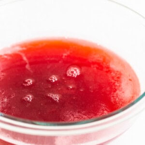 A bowl of red liquid on a white surface.